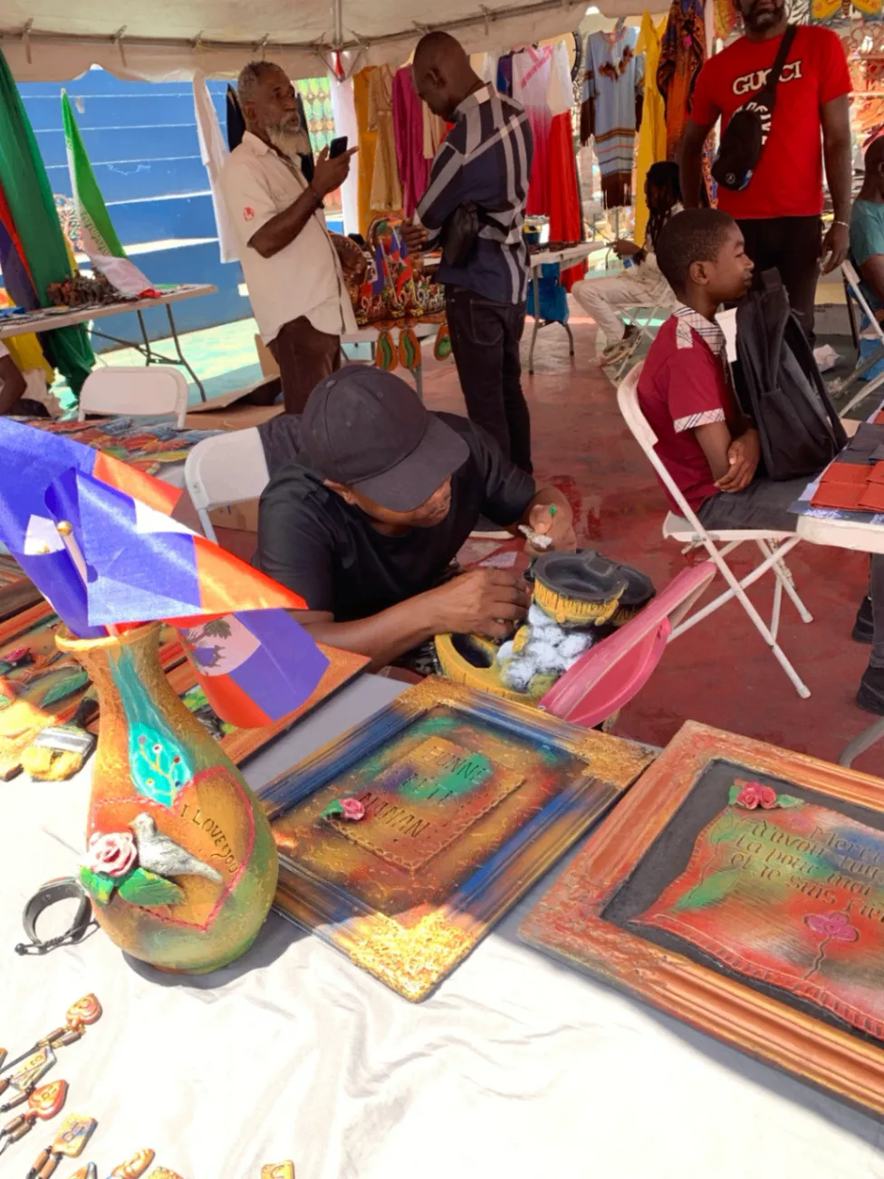 Painted gourds and framed Haitian artwork at an artisan market.